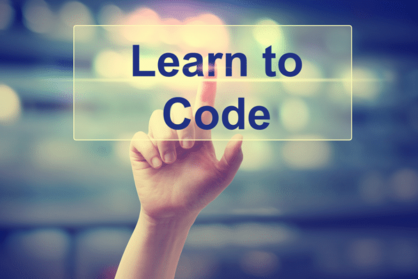 Auf dem Bild ist der Schriftzug "Learn to Code" zu lesen. Dahinter ist eine Hand, die darauf tippt und die Schrift hell erleuchten lässt.